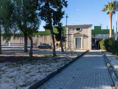 Superiamo dunque l�accesso per entrare in un vasto cortile utilizzato dall�impresa di autonoleggio come parcheggio per le macchine. E sulla destra ecco apparire la cappella. Notiamo subito come il piccolo edificio, di color rosa pallido, sia di fatto attaccato a un alto muro: quello che separa l�area dalla sovrastante via Tatarella